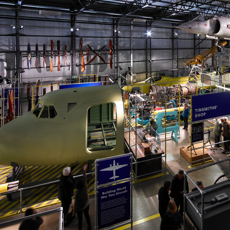 Exhibit on aircraft construction in a museum, featuring a large plane fuselage, engine models, propellers, and visitor displays.