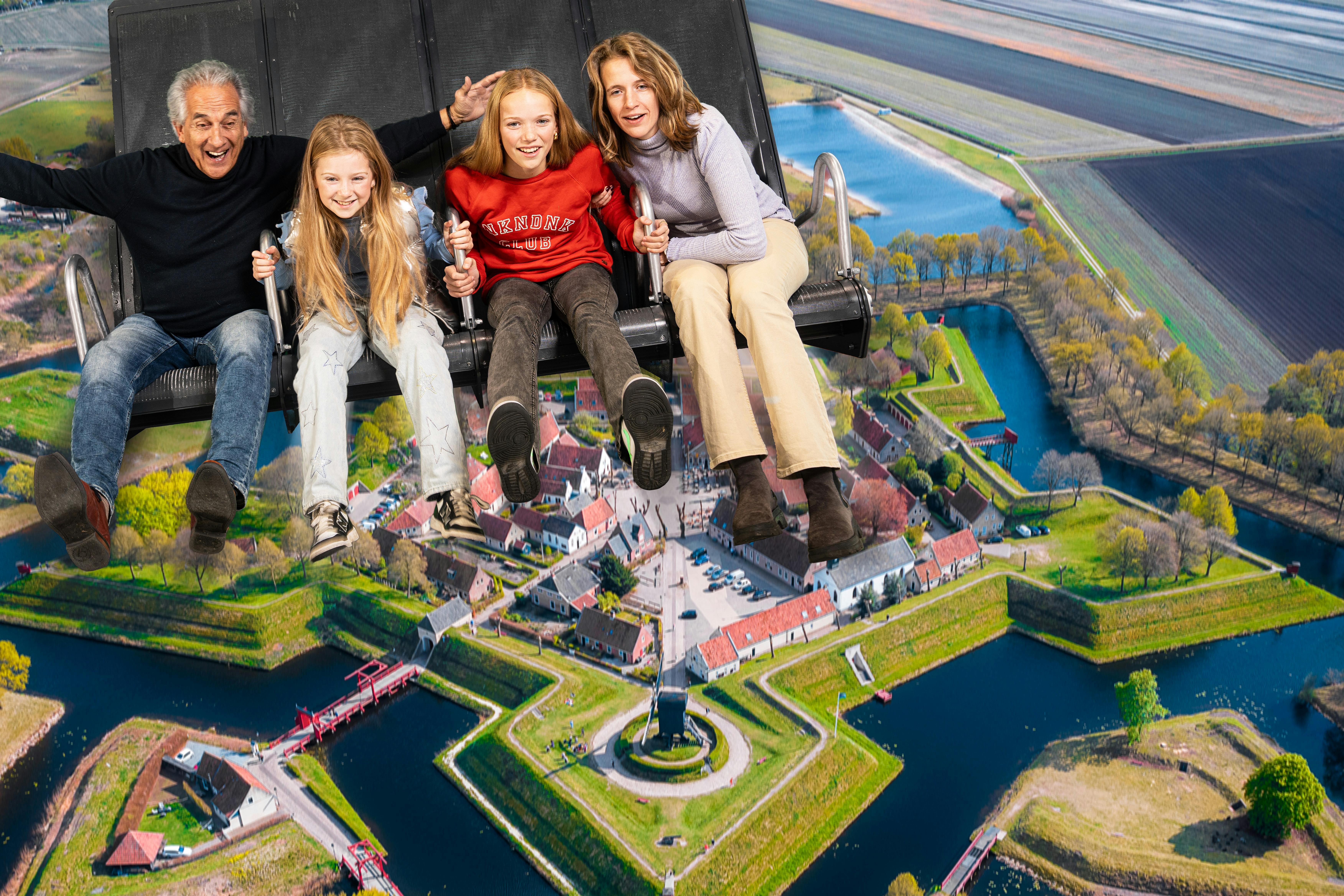 Vier personen, twee volwassenen en twee kinderen, tijdens een ritje hangend boven een gedetailleerd bovenaanzicht van een historisch sterfort met grachten.