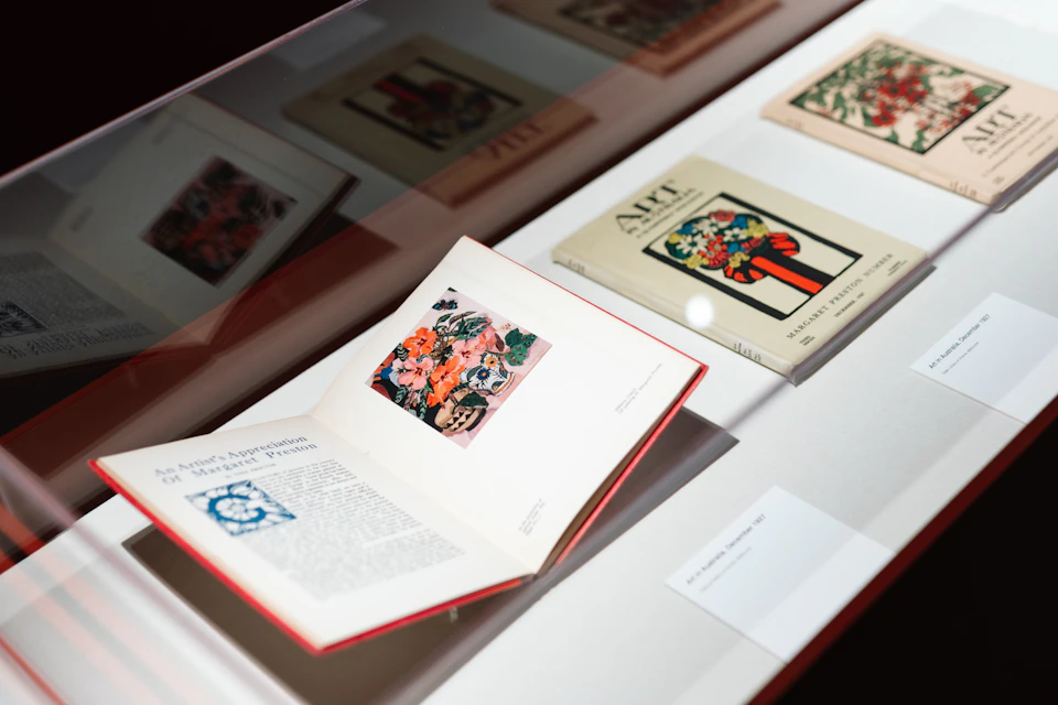 Open and closed books displayed in a museum exhibit, featuring colorful floral illustrations and text.