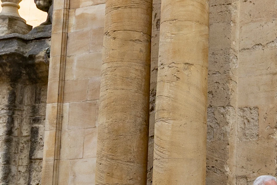 A group of people standing near a historic building with tall columns and a large wooden door.