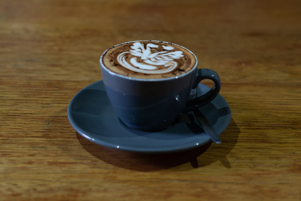 A cup of cappuccino with latte art on a wooden table.