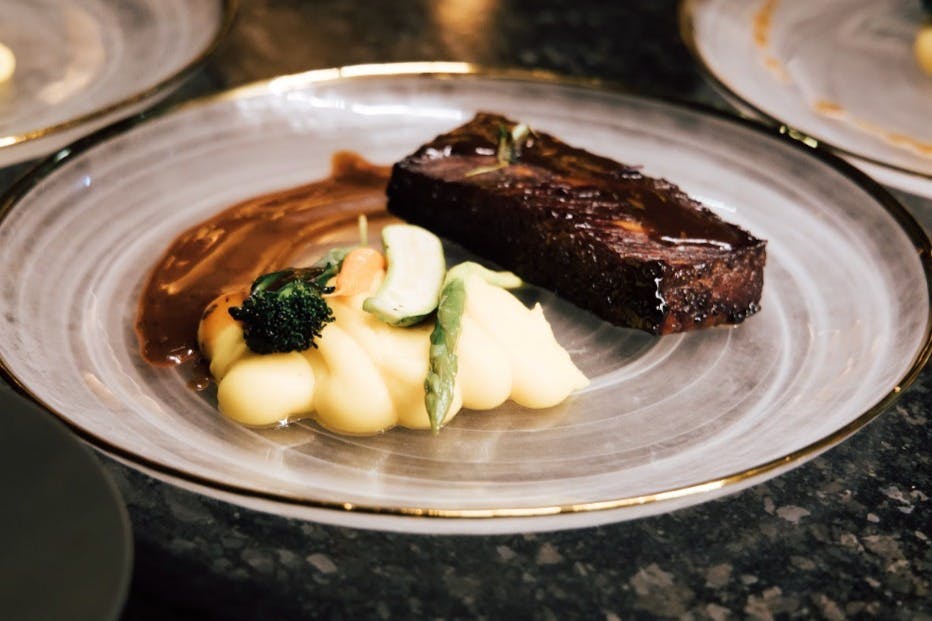 一道镀有釉面的肉片、土豆泥和蔬菜的盘子。