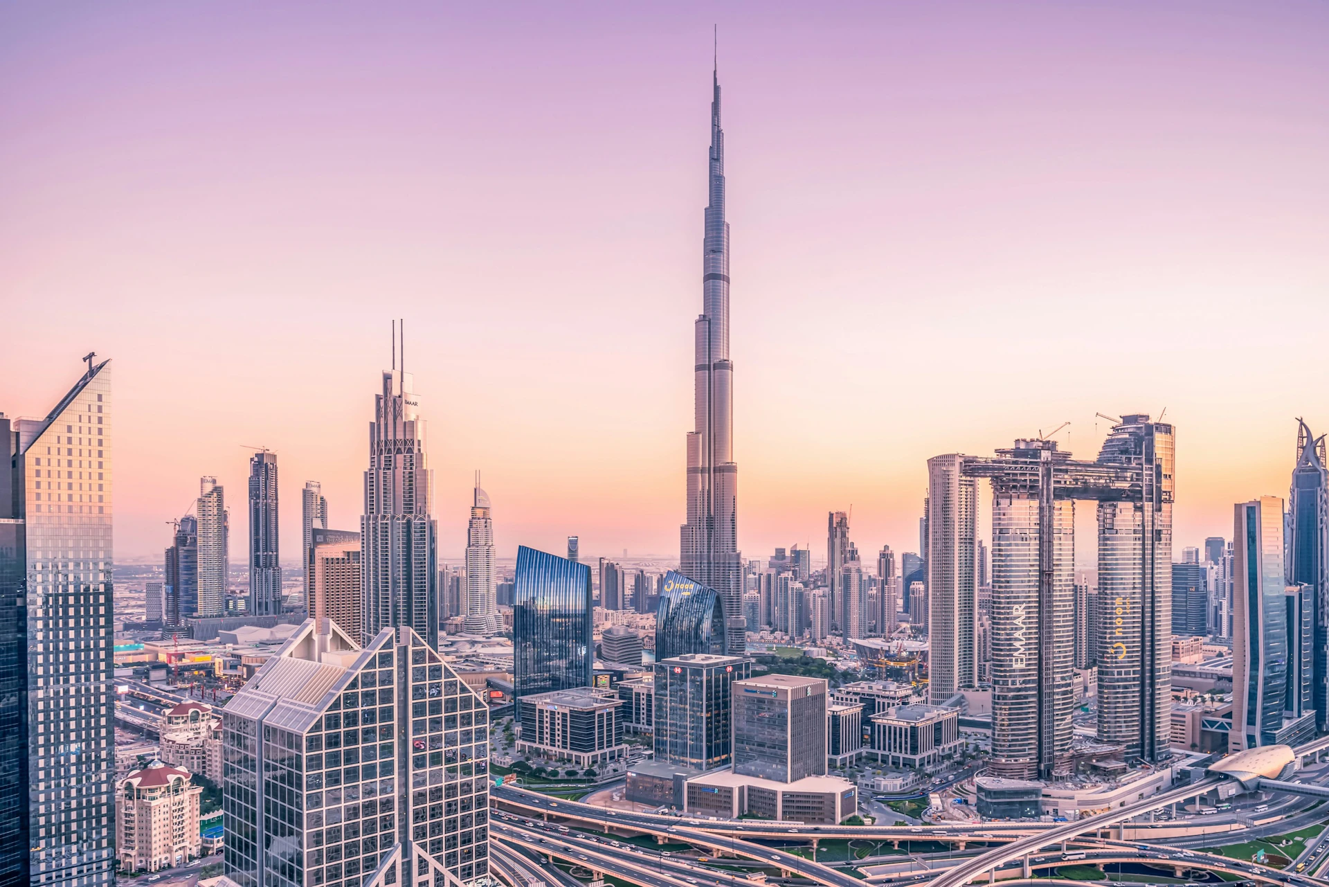 A skyline featuring skyscrapers at dusk, with a prominent tall building in the center and a soft gradient sky in the background.