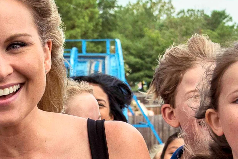A woman and a young girl smiling and enjoying a rollercoaster ride, with blue and green tracks visible in the background.