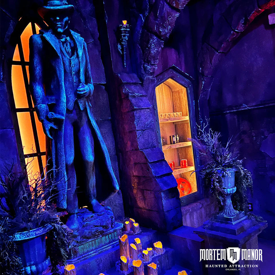 Dimly lit gothic room with a statue of a man in a hat. Shelves with books and potions. Eerie lighting and candles around.