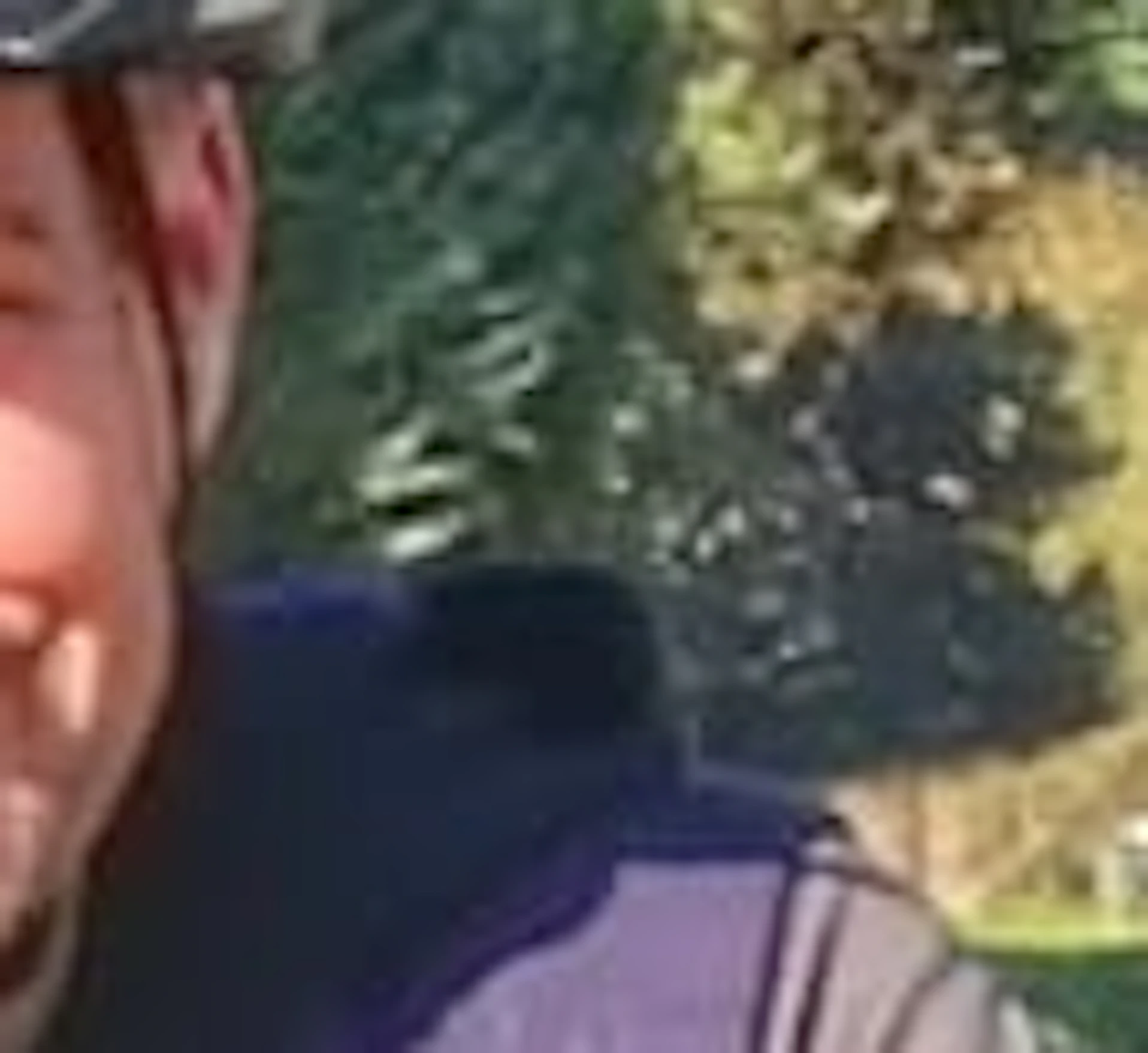 People wearing helmets riding bicycles on a cobblestone path surrounded by greenery and trees on a sunny day.