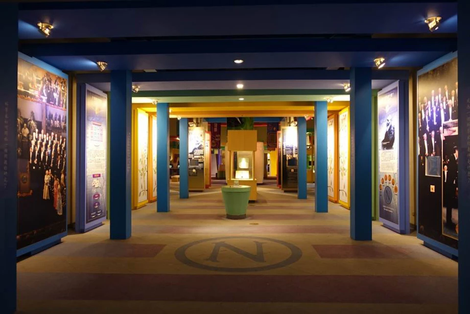 A brightly lit hallway with colorful walls and informational displays, featuring a compass design on the floor.