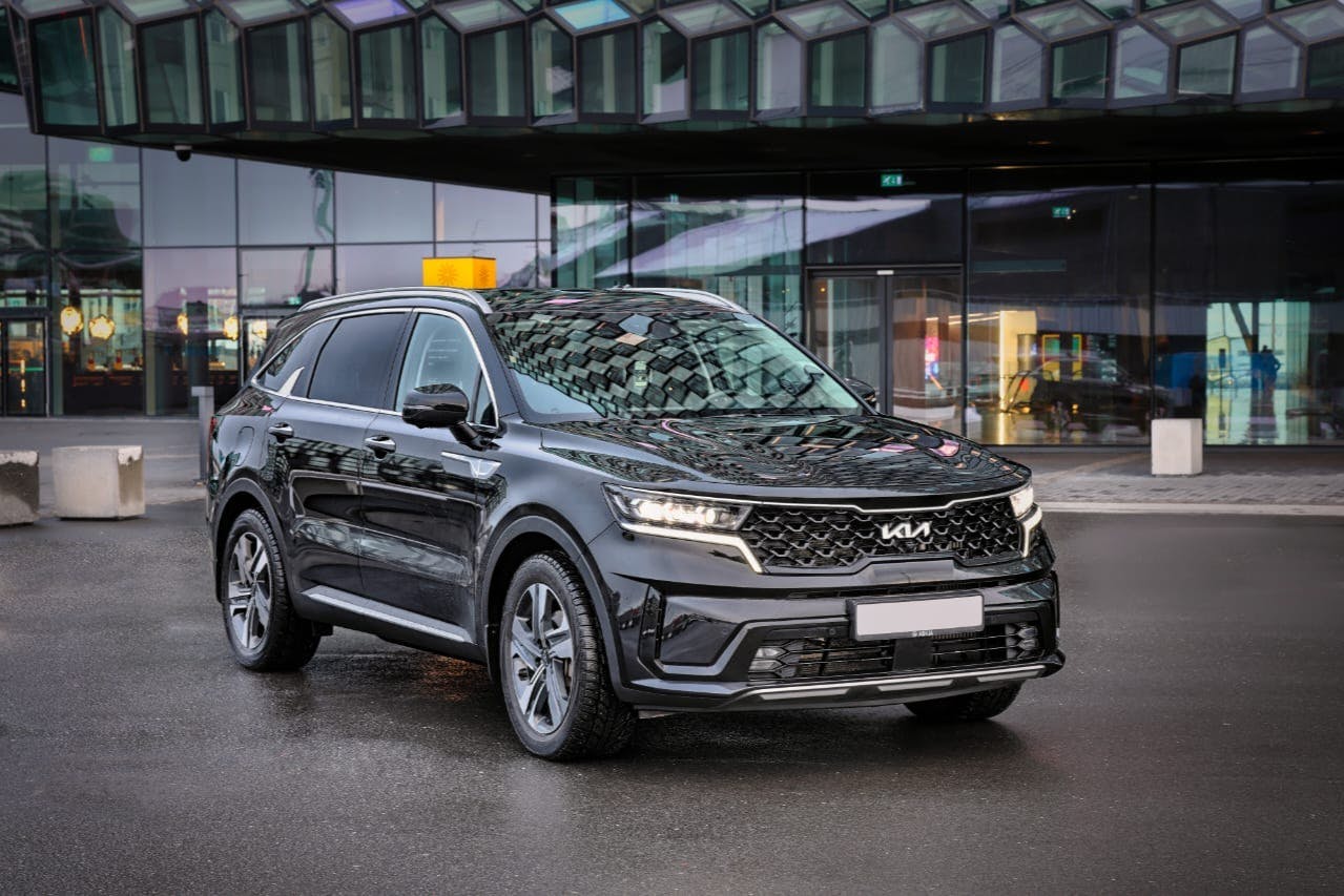 A black SUV parked on a wet street in front of a modern glass building.