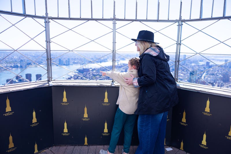 En voksen og et barn står på et observationsdæk. Barnet peger udad, mens den voksne forsigtigt holder om skulderen.