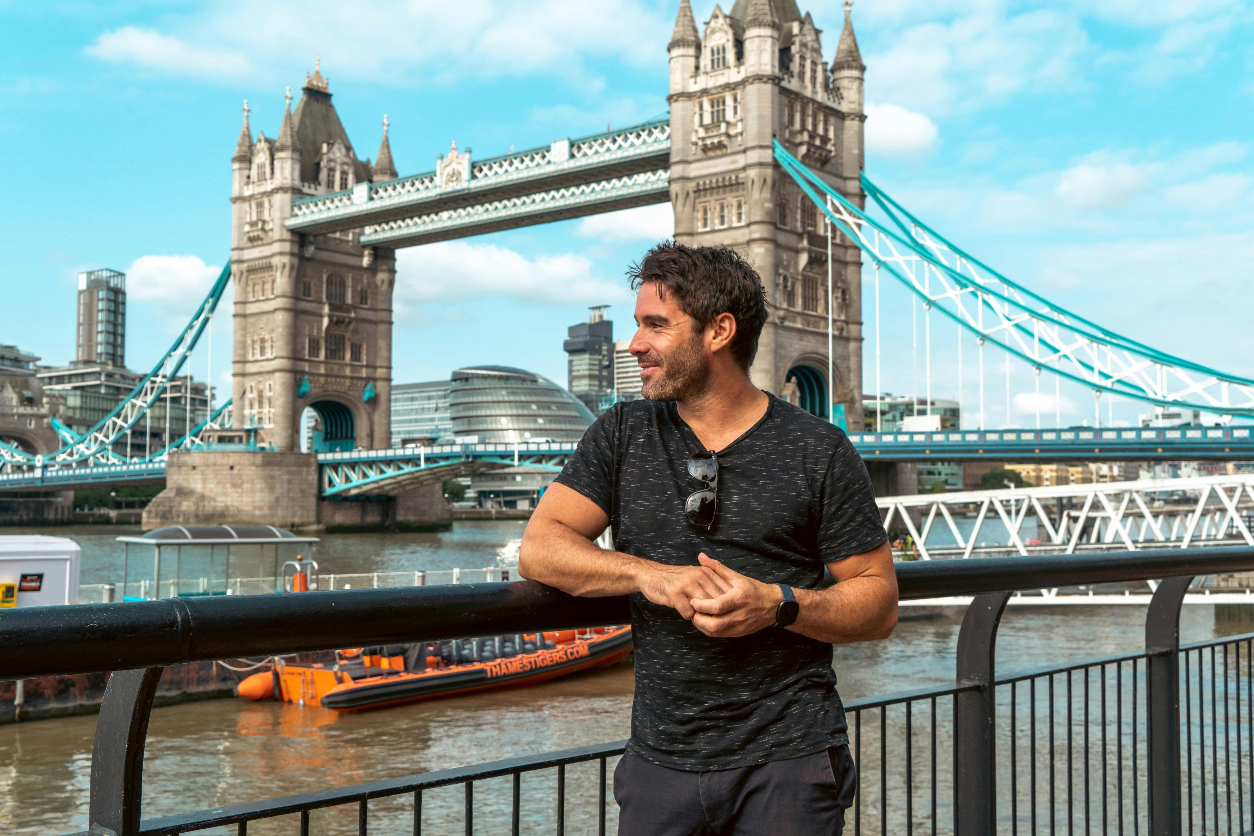A tourist is having his photo taken outside the Tower Bridge.