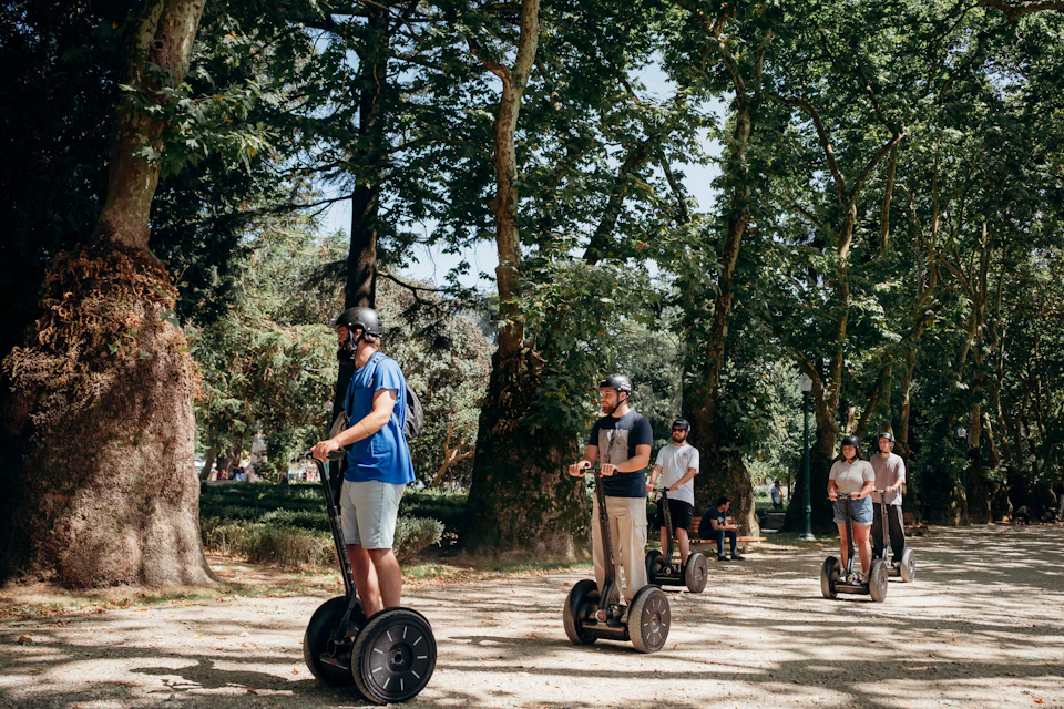 People riding Segways on a tree-lined path in a park.
