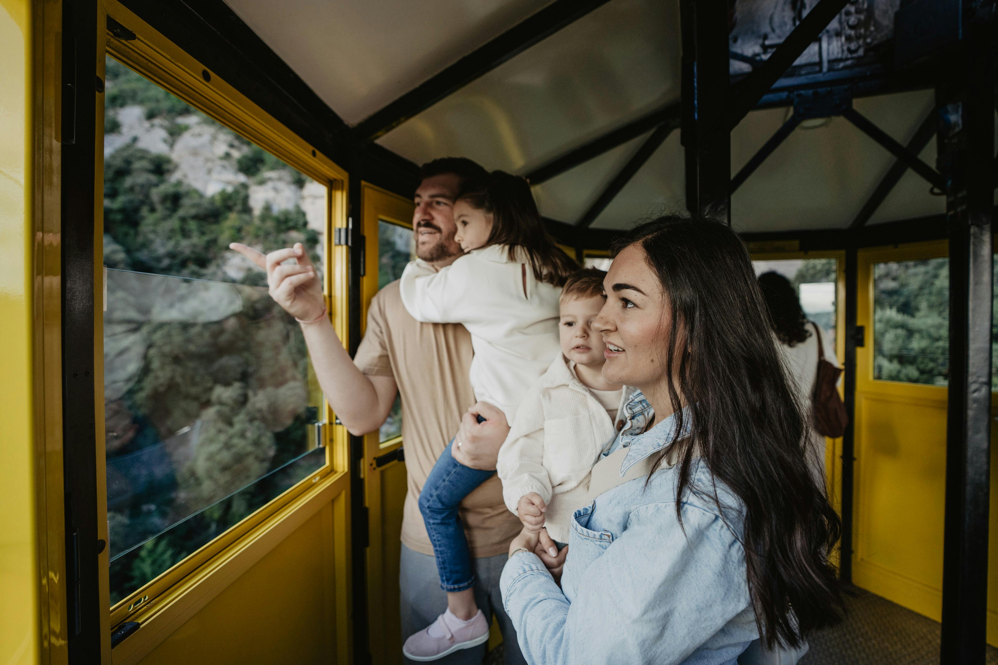 Una familia de cuatro miembros dentro de un teleférico amarillo, mirando las vistas por las ventanillas.