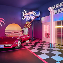En person står bredvid en röd cabriolet i ett rum med retro-tema med neonskyltar, ett rutigt golv och en "Music Shop" -butik.