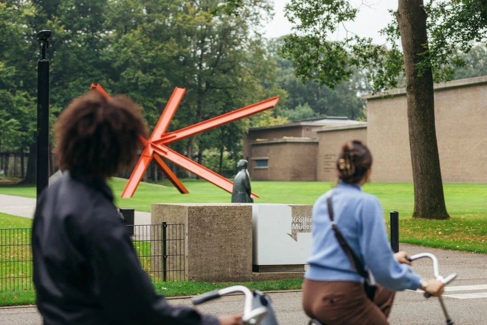 Visitors on white bikes in front of the Kröller-Müller Museum
