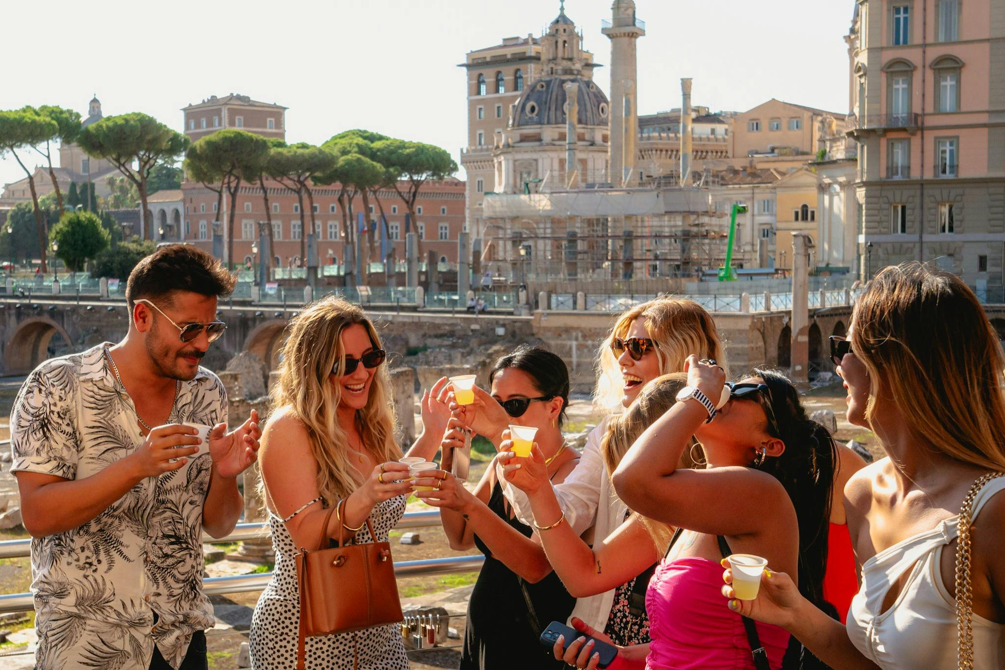 역사적인 건물과 나무를 배경으로 야외에서 음료를 즐기는 사람들의 모임.