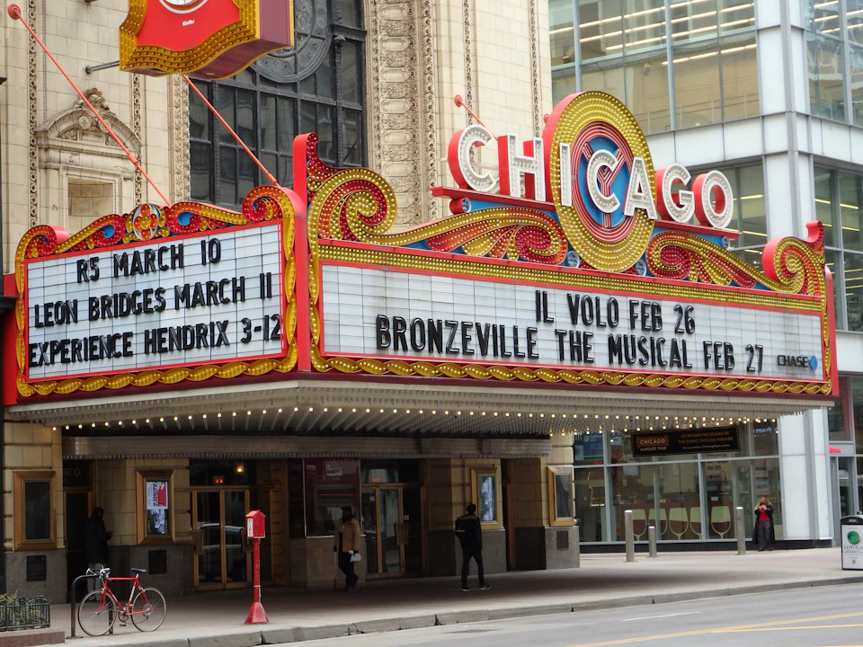 Chicago Theatre marquee displaying upcoming events, including Il Volo, Bridges, and Jimi Hendrix tribute. Street and entrance visible.