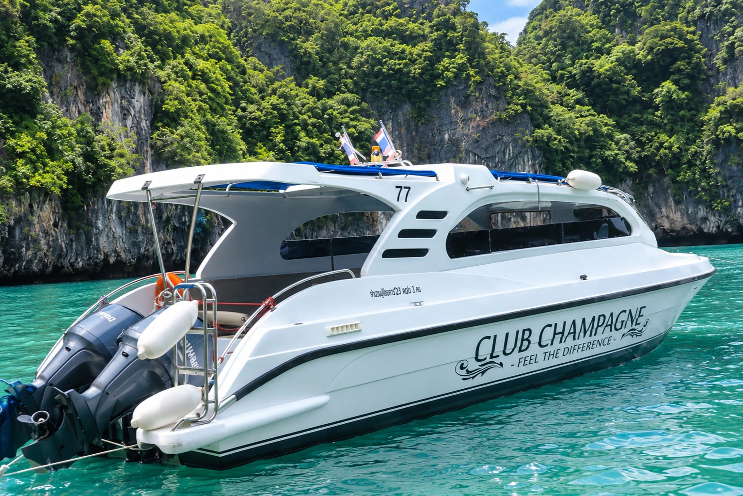 A white motorboat named 'Club Champagne' floating in turquoise water, with a forested cliff in the background.