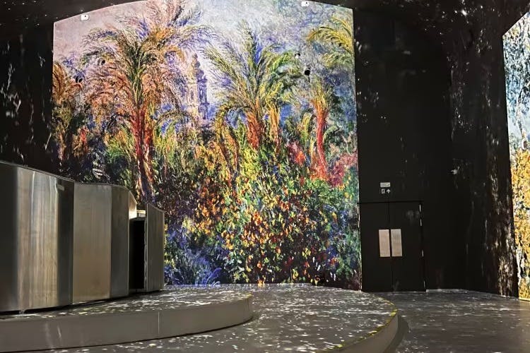 Яркая настенная роспись с высокими пальмами и густой листвой в тускло освещенной комнате со сценой и изогнутой платформой.