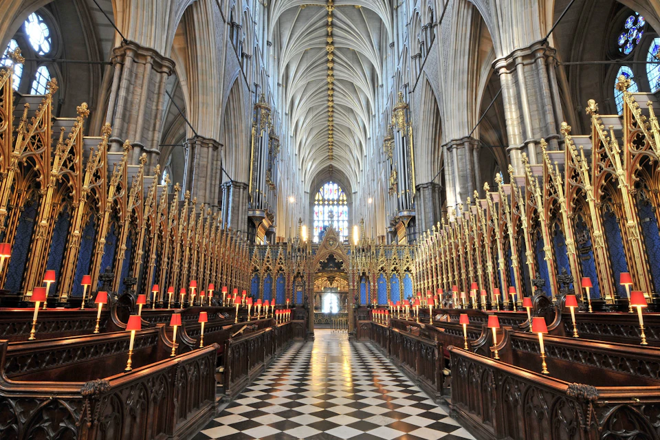 A grand cathedral interior with vaulted ceilings, ornate decorations, and a checkered floor leading to a stained glass window.