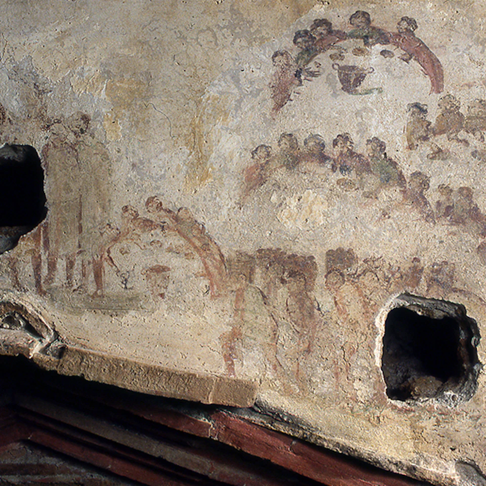Ancient fresco depicting a banquet scene with multiple figures seated and standing, some damage with visible holes in the wall.
