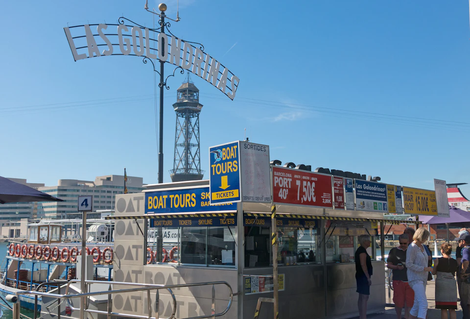 Ticket booth for boat tours under a sign reading "Las Golondrinas," with a tall tower and other buildings in the background.