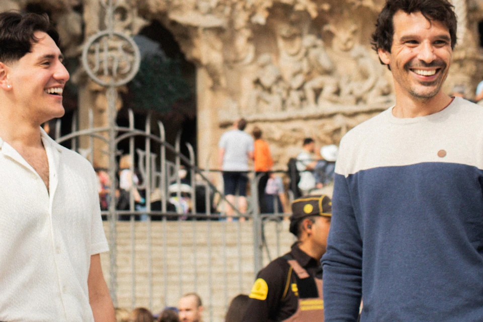 Four people smiling and chatting in front of a detailed stone facade of a large historic building in a busy setting.