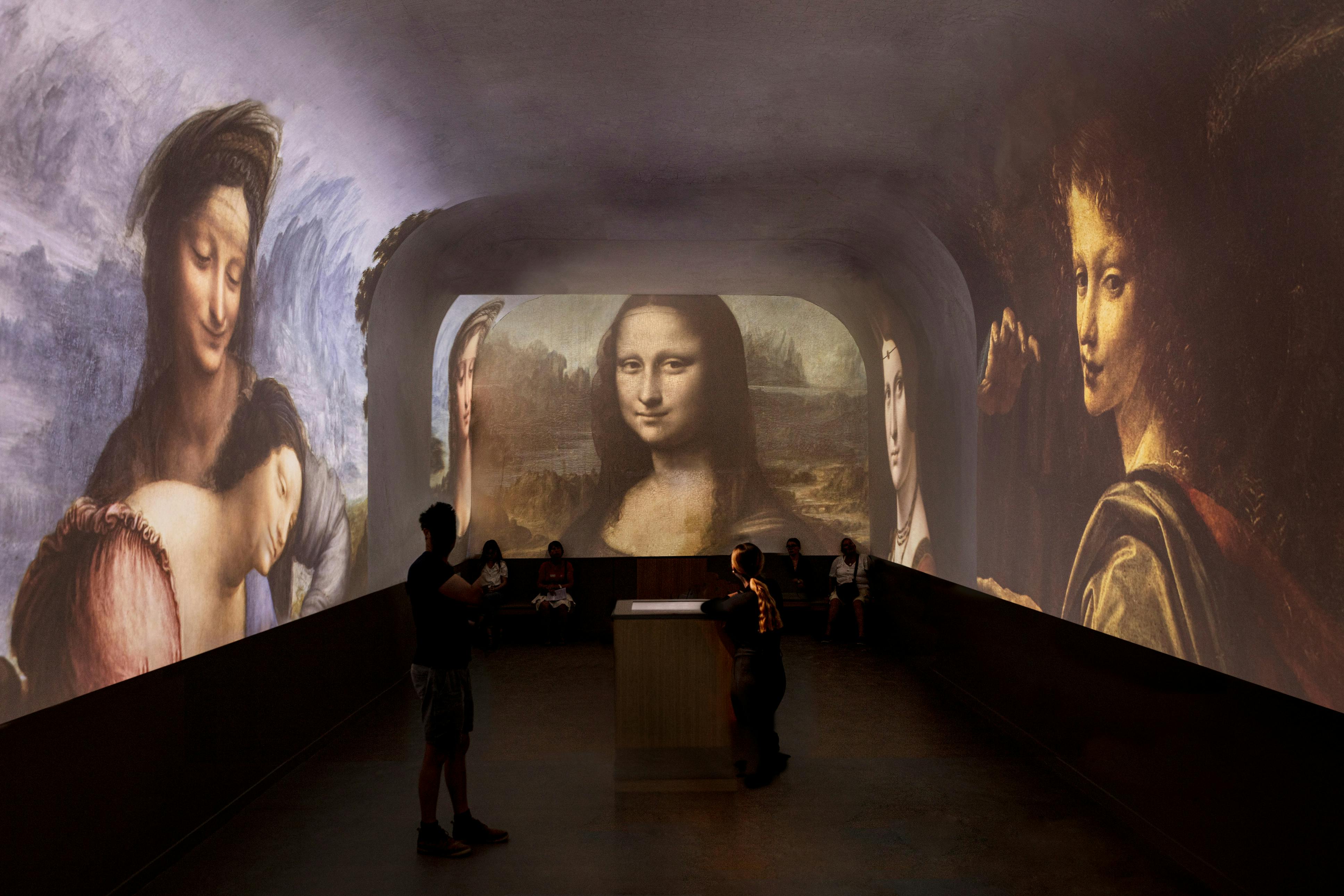 Una sala con imágenes proyectadas de cuadros famosos, como la Mona Lisa, y gente observando la exposición.