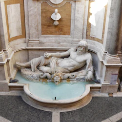 Marmorstaty av en liggande skäggig figur i en fontän-nisch, omgiven av pelare, med en byst ovanför på väggen.