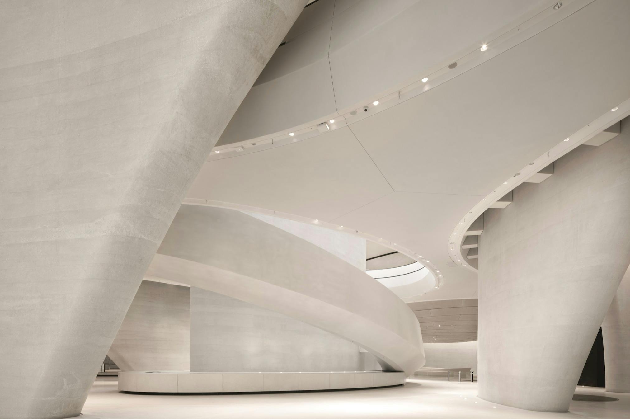 Moderní interiér se zakřivenými, hladkými, bílými architektonickými prvky a měkkým osvětlením.