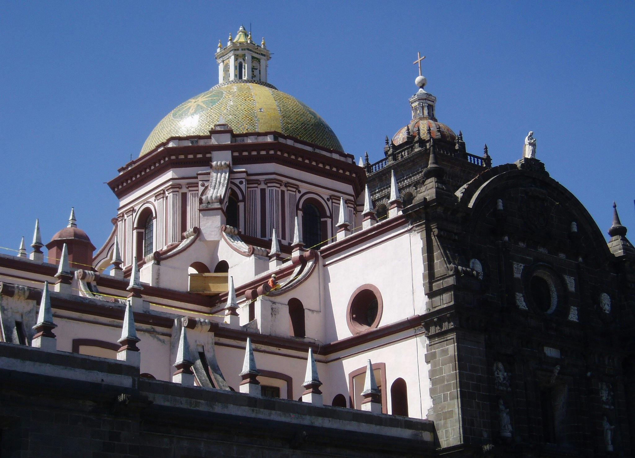 돔형 노란색 타일 지붕, 아치형 창문, 맑고 푸른 하늘을 배경으로 장식된 첨탑이 있는 화려한 교회.