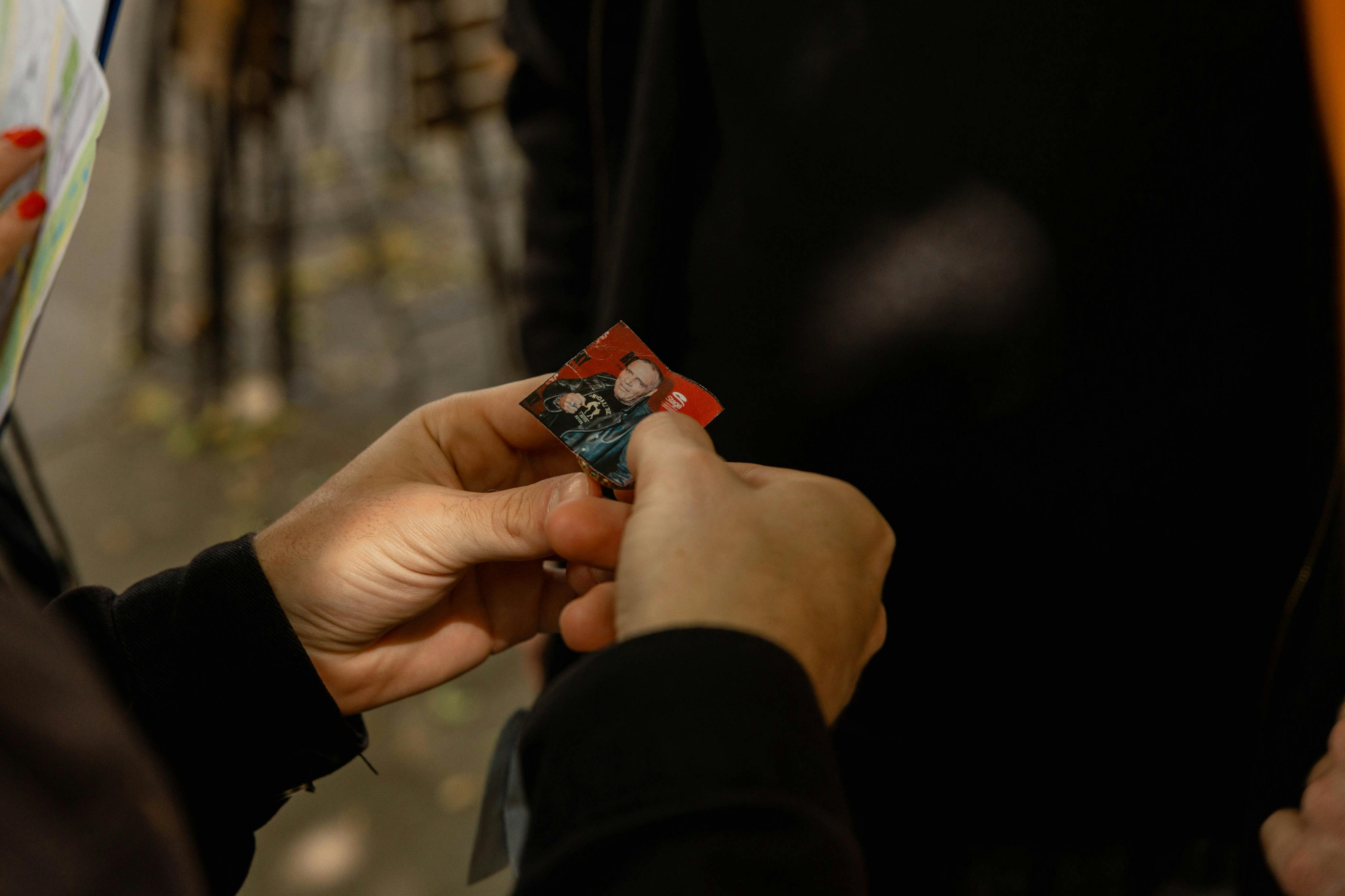 一个人拿着一张小照片，手里拿着一张小照片，里面有户外背景模糊不清的人和另一个人。