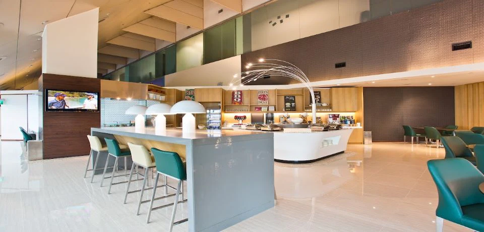 Modern cafe interior with a counter, chairs, decorative lighting, and shelves displaying items in the background.