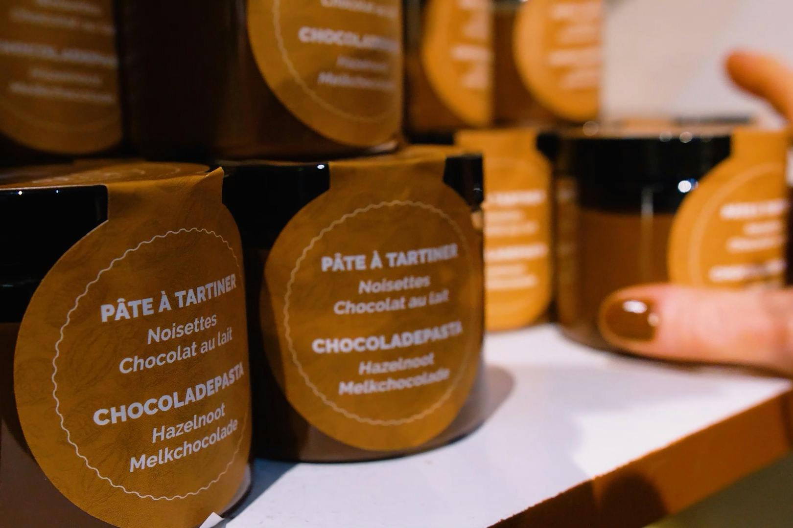 Various jars of hazelnut chocolate spread with orange labels stacked on a shelf.