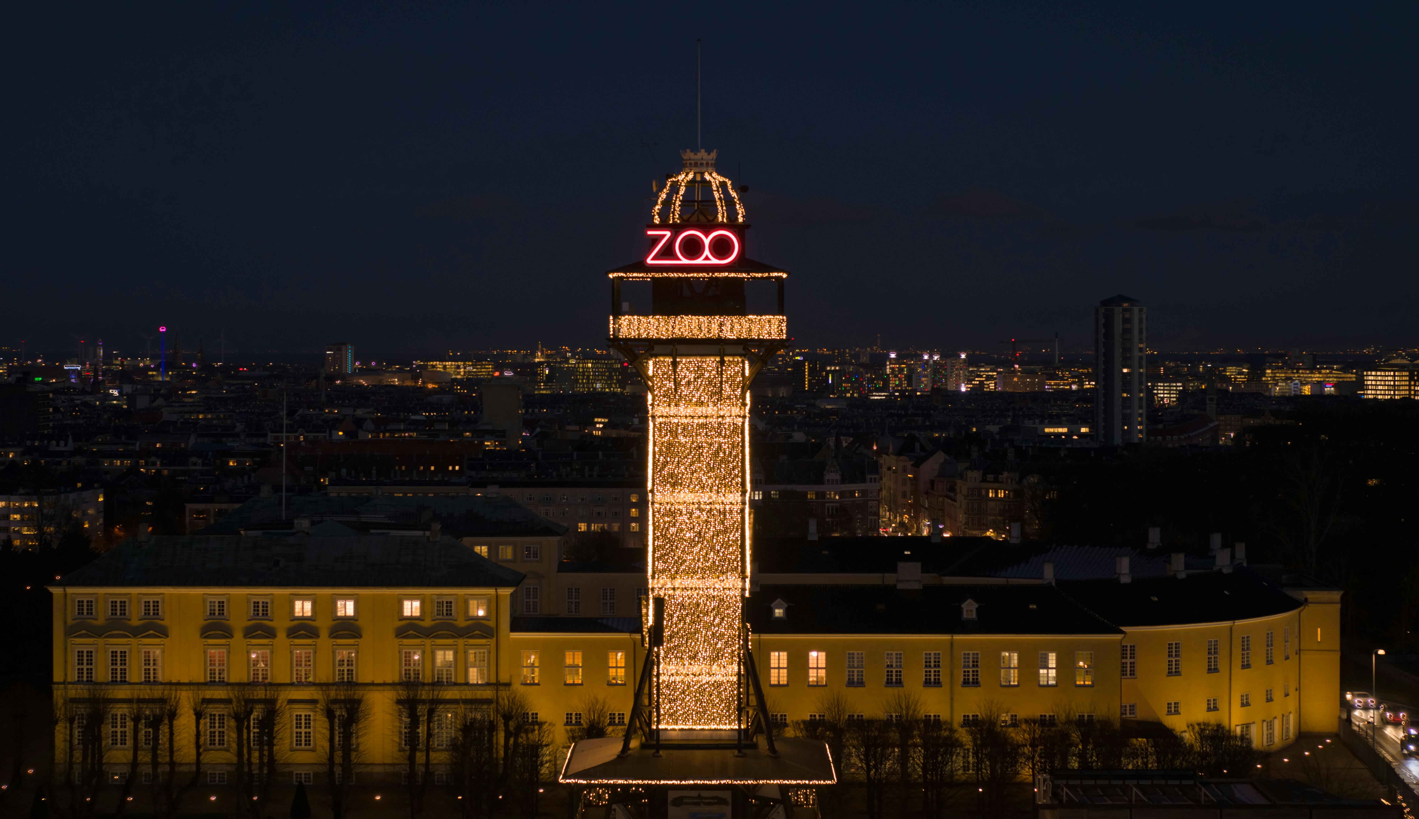 上部に赤いネオンの「動物園」がある高くて明るい塔は、夜には暗い街並みに立ち向かいます。