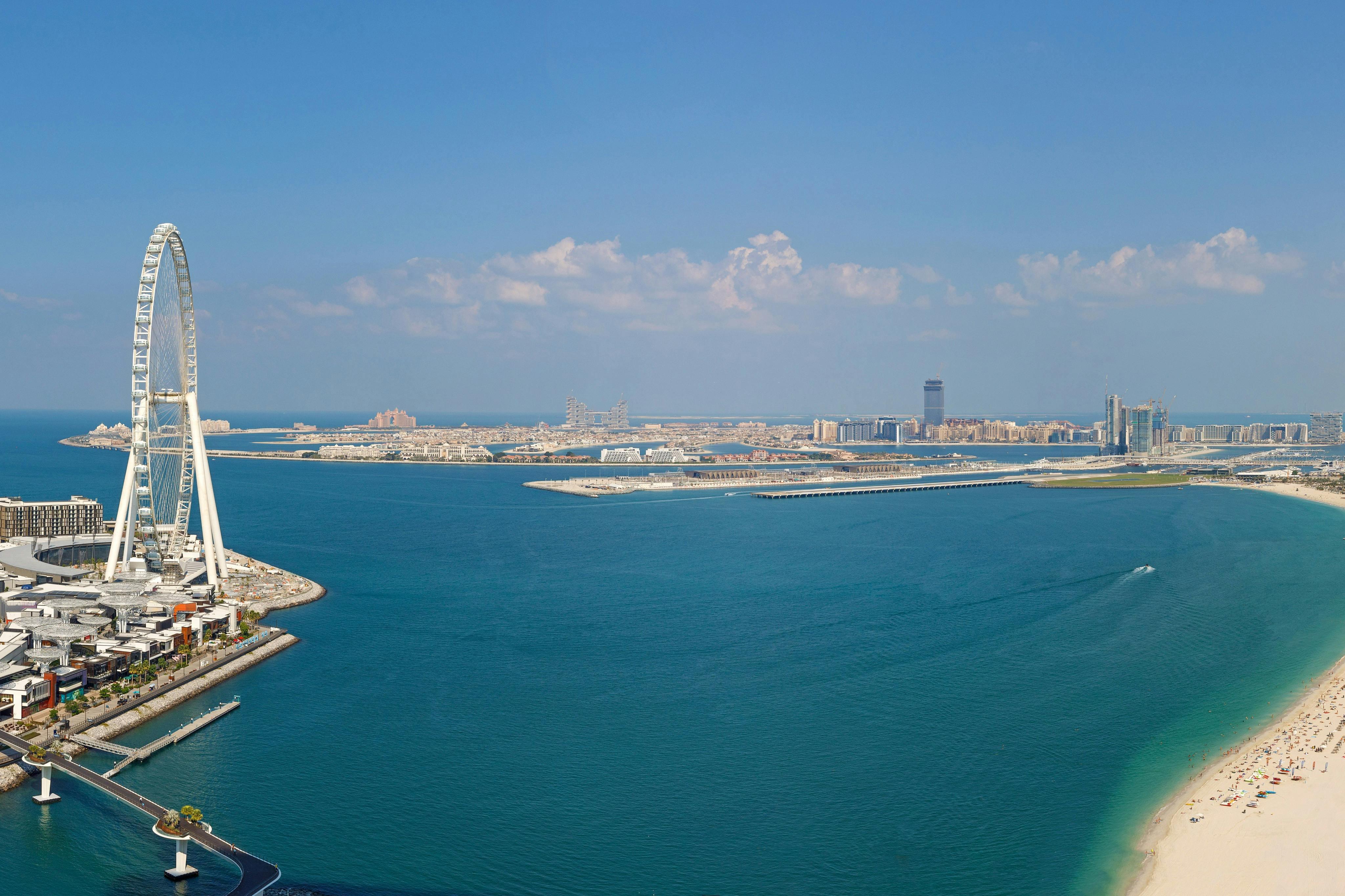 島々、建物、広大な水域、青い空と散らばった雲が広がる海岸沿いの街並み。
