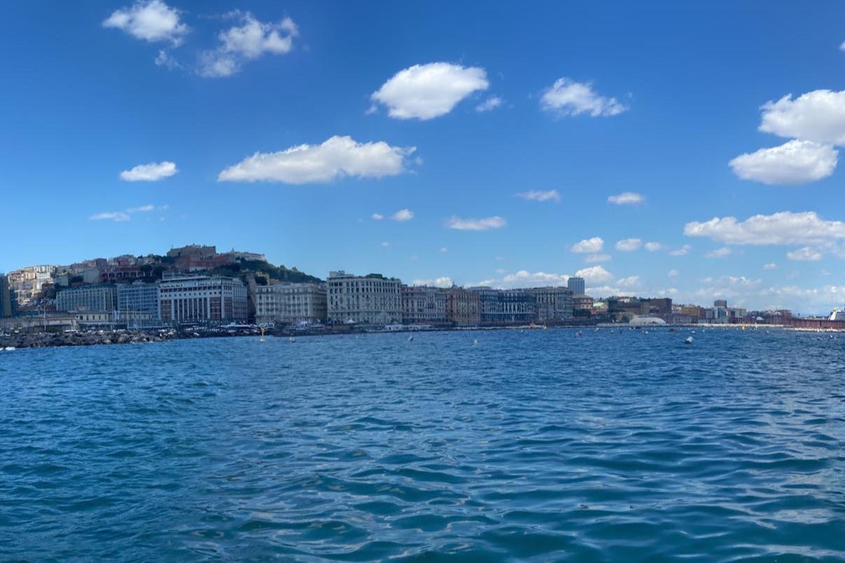 Vista junto al agua de un paisaje urbano con múltiples edificios a lo largo de la costa, bajo un cielo azul con nubes dispersas.