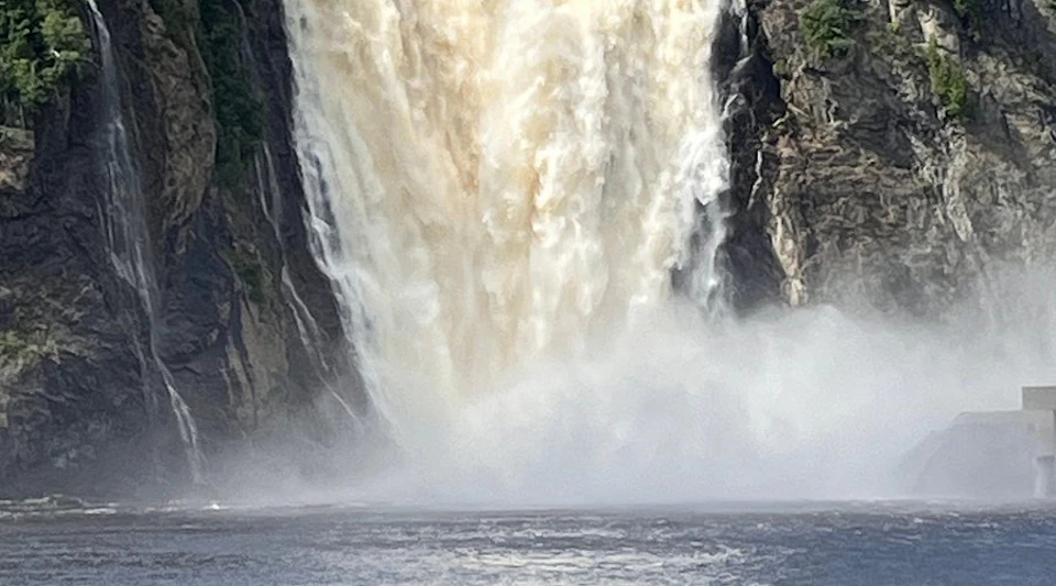 A powerful waterfall cascading over rocky cliffs, creating mist as it crashes into the water below.