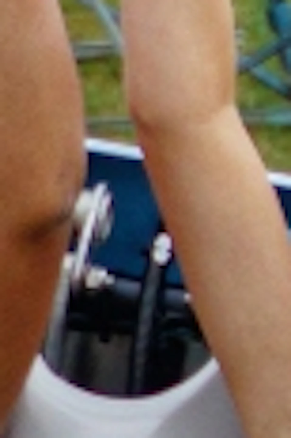 Two smiling women with raised arms ride a blue cart on a track at Rowdy Bear Amusement Park, with other riders in the background.