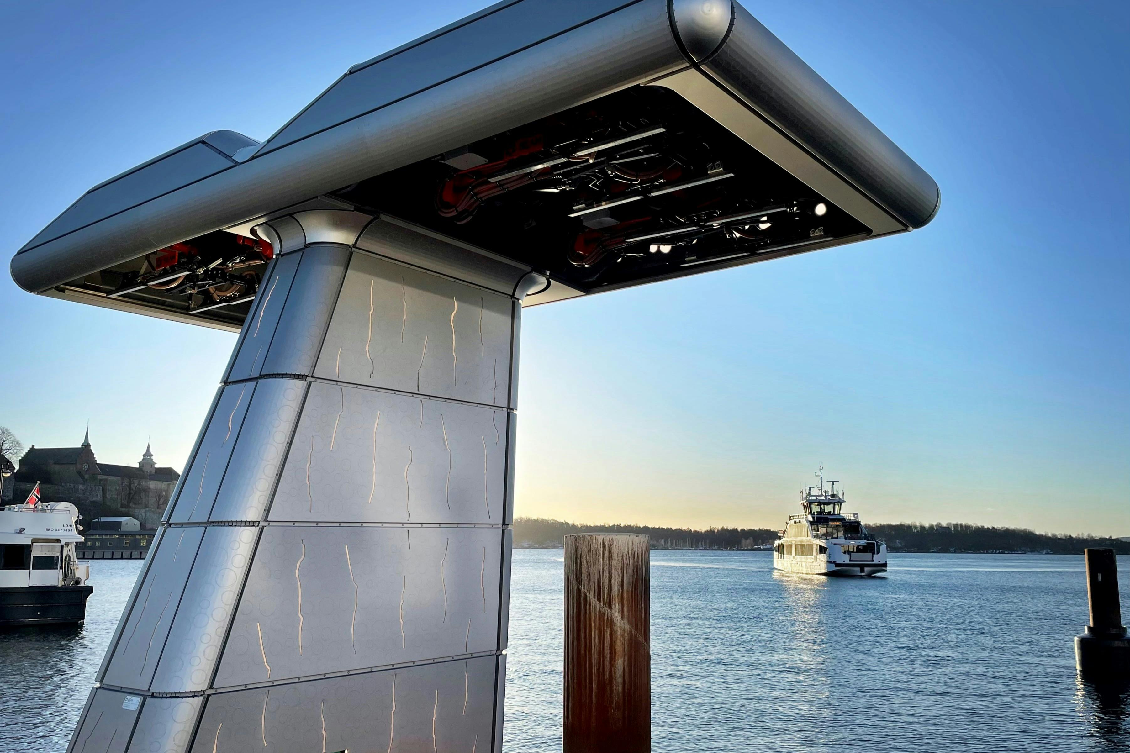 A modern structure by the water with a boat in the distance under a clear sky.