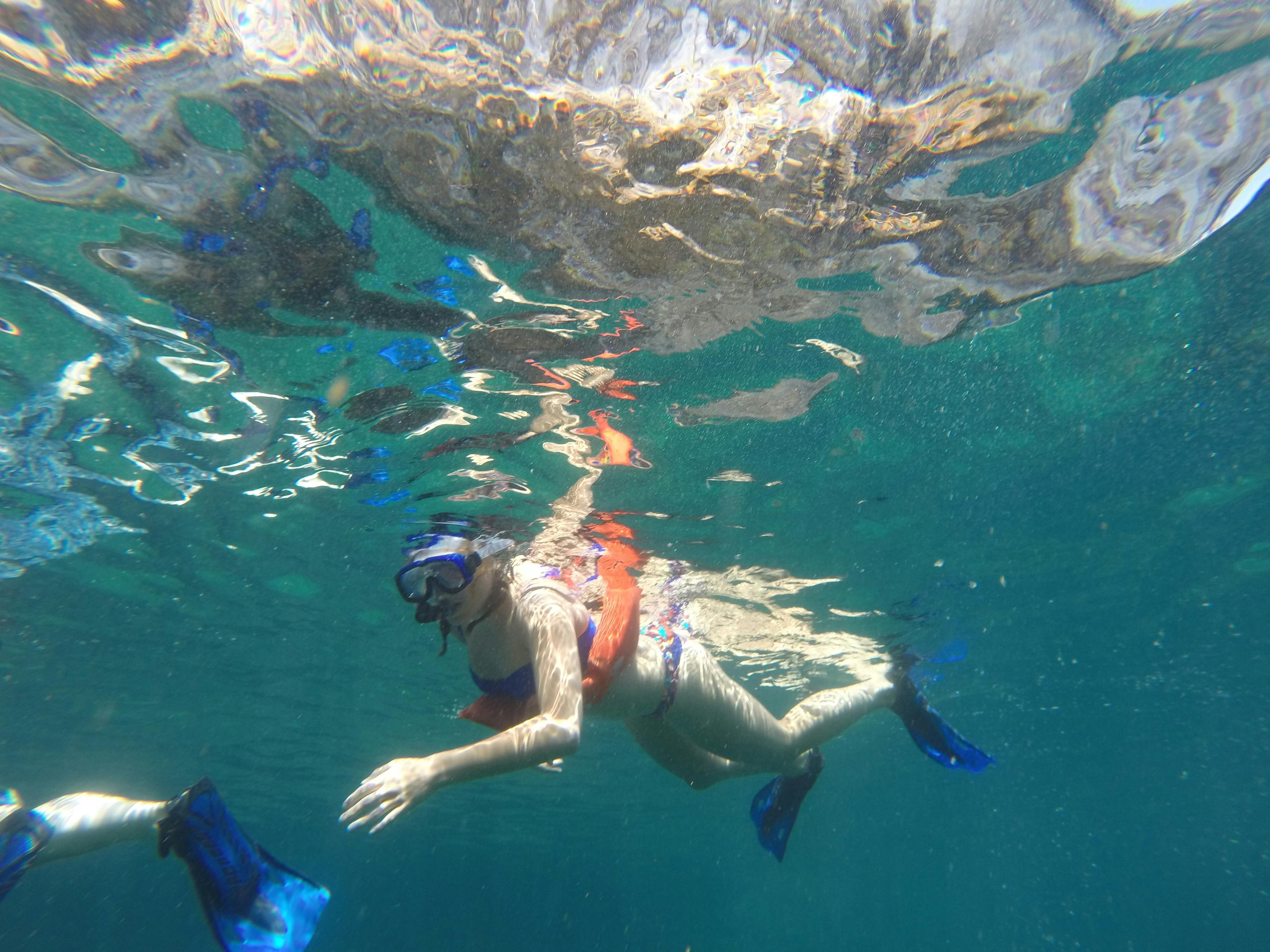 맑고 푸른 물로 둘러싸인 수중에서 마스크, 스노클링, 푸른 오리발을 착용하고 스노클링을 즐기는 사람.