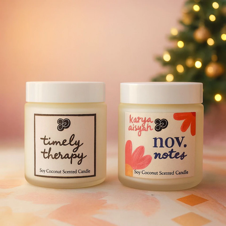 Two soy coconut-scented candles in frosted glass jars with white lids, placed on a soft pastel background. A blurred Christmas tree with lights is in the background.