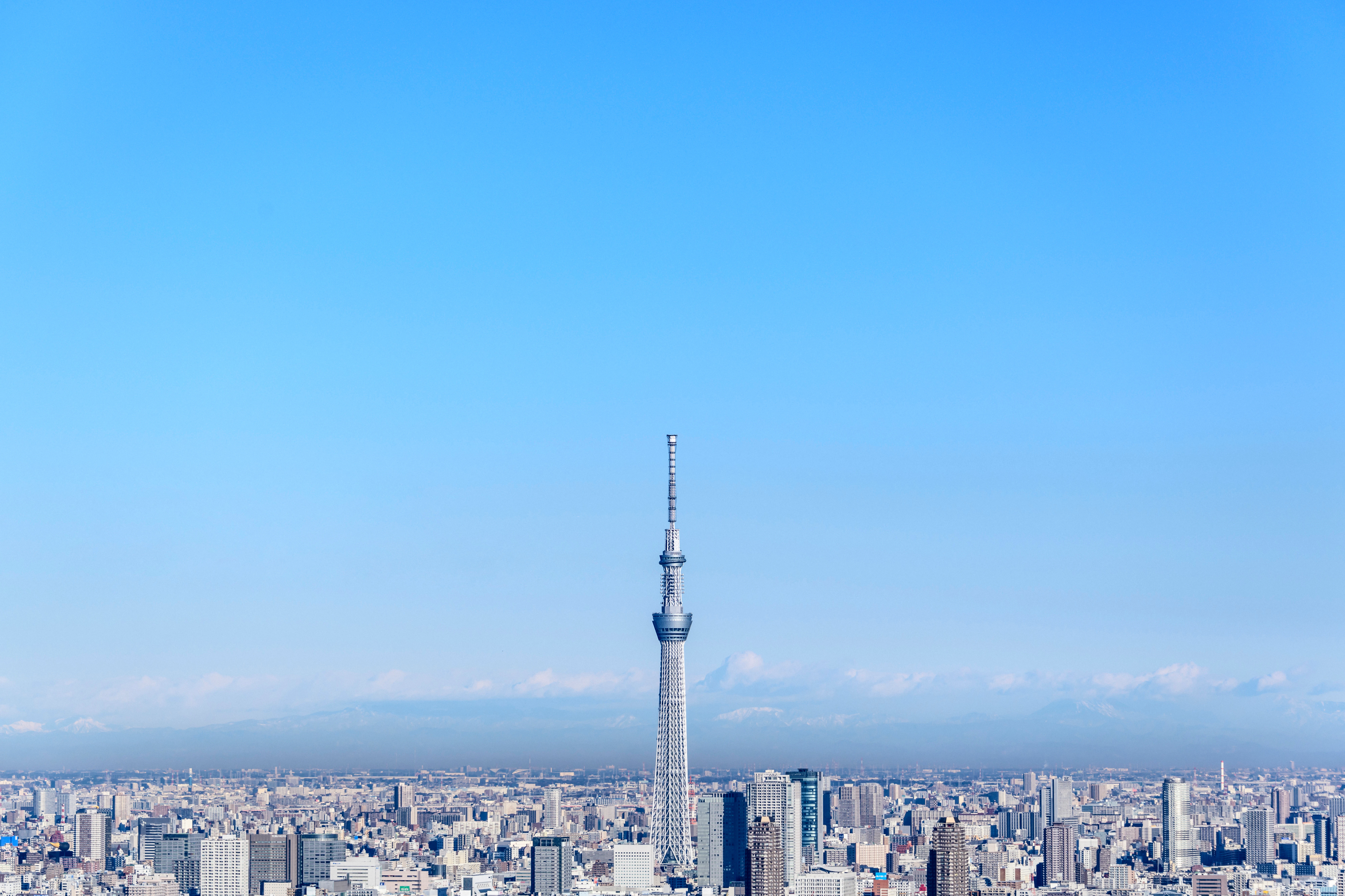 A tall tower stands amid a vast cityscape under a clear blue sky.