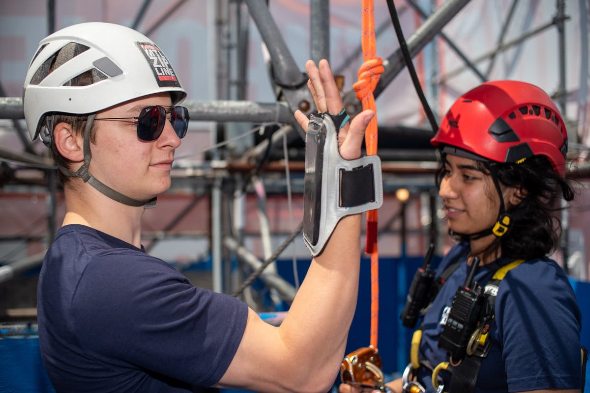 Due persone che indossano caschi e dispositivi di sicurezza interagiscono con l&#39;attrezzatura da arrampicata su una struttura di impalcatura.