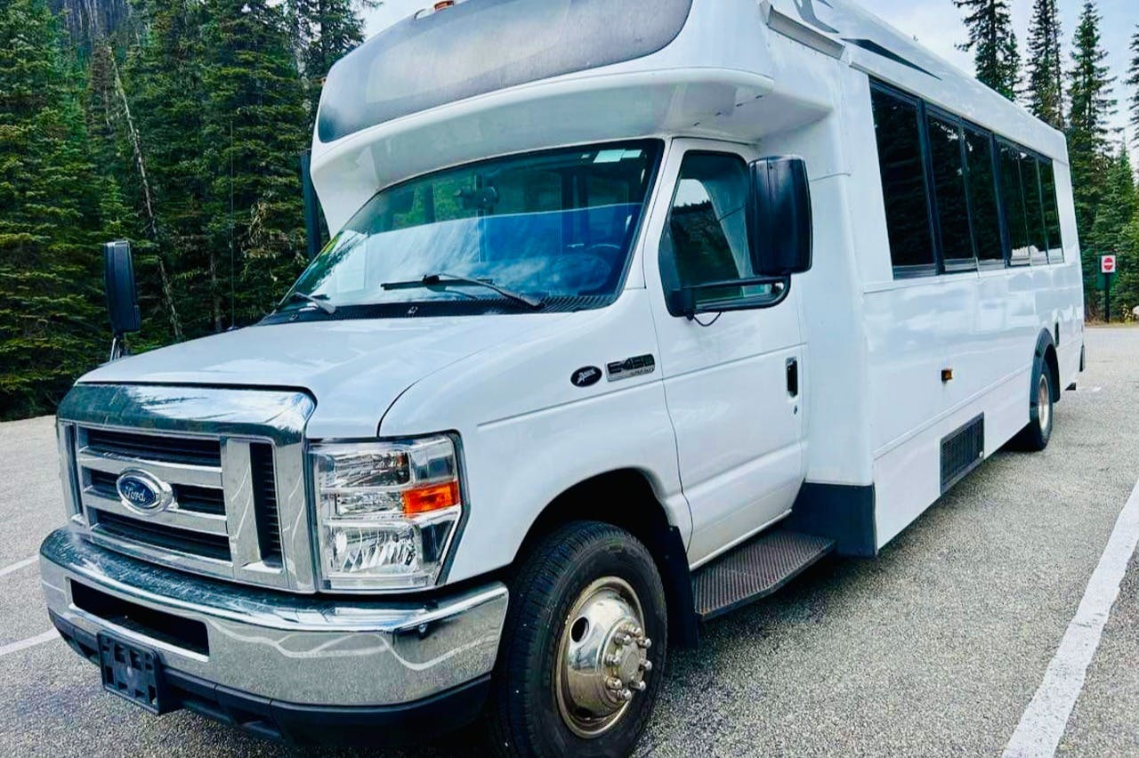 A white recreational vehicle is parked on a paved surface, with trees visible in the background.