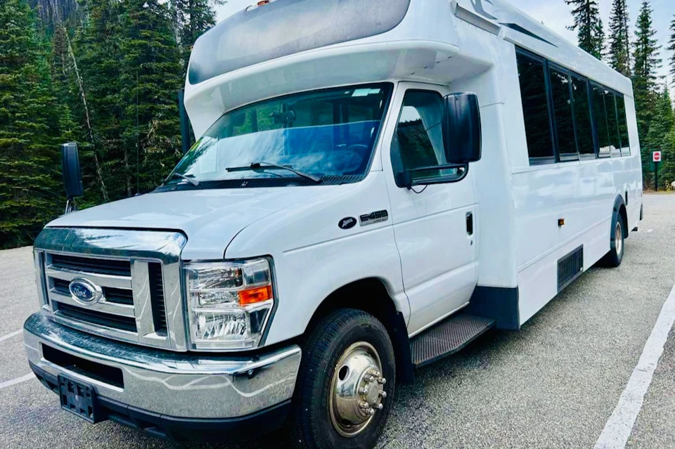 A white recreational vehicle is parked on a paved surface, with trees visible in the background.