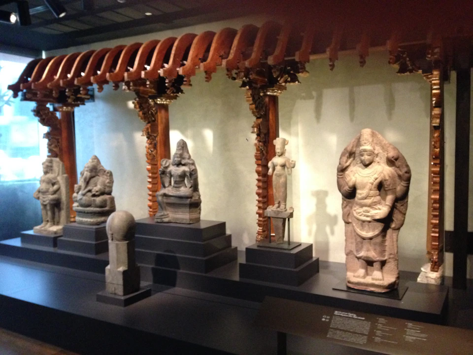 Ornate wooden arches and stone sculptures displayed in a museum exhibit.