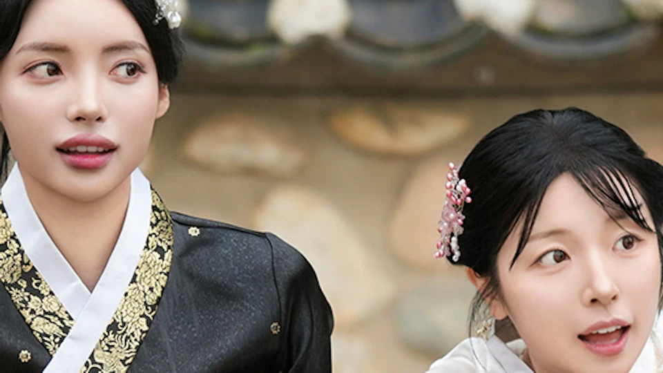 Two women in traditional Korean hanbok attire lean on a tiled wall, looking in different directions with curious expressions.