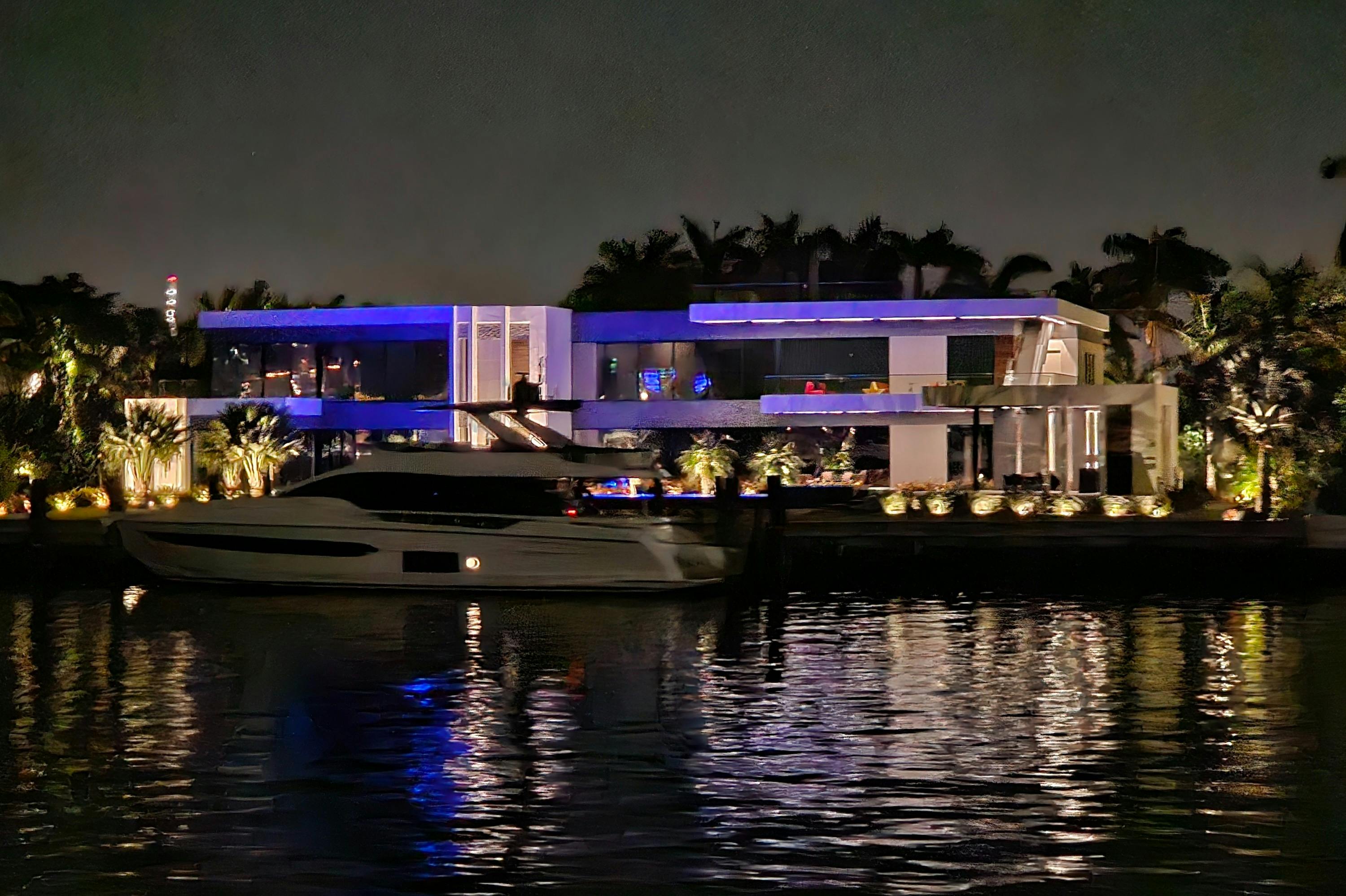 Millionaire's Home bei Nacht beleuchtet mit ihrer Yacht vor der Tür