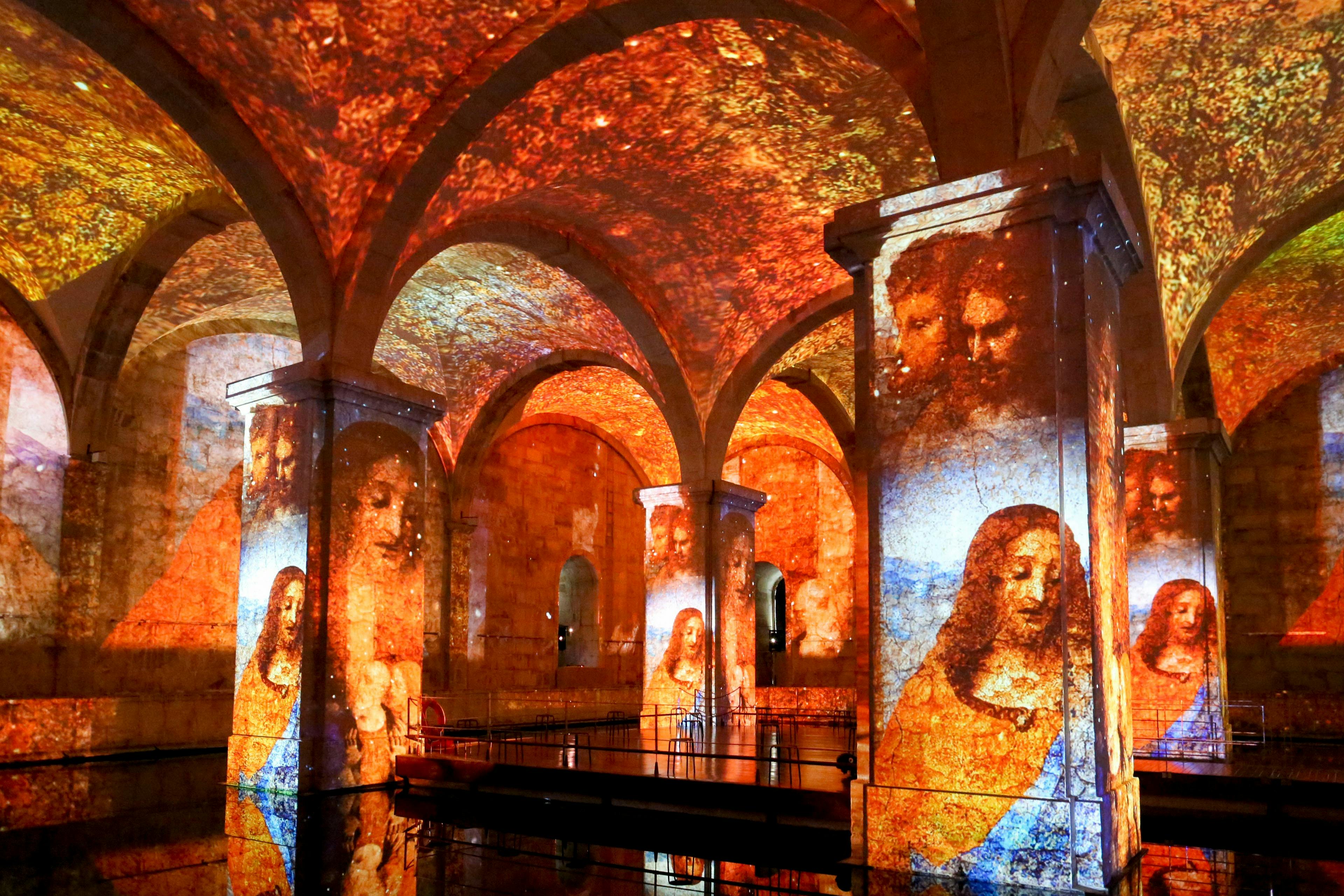 ルネッサンス期の芸術作品が映し出された、アーチ型の天井と柱を備えた展示スペース。