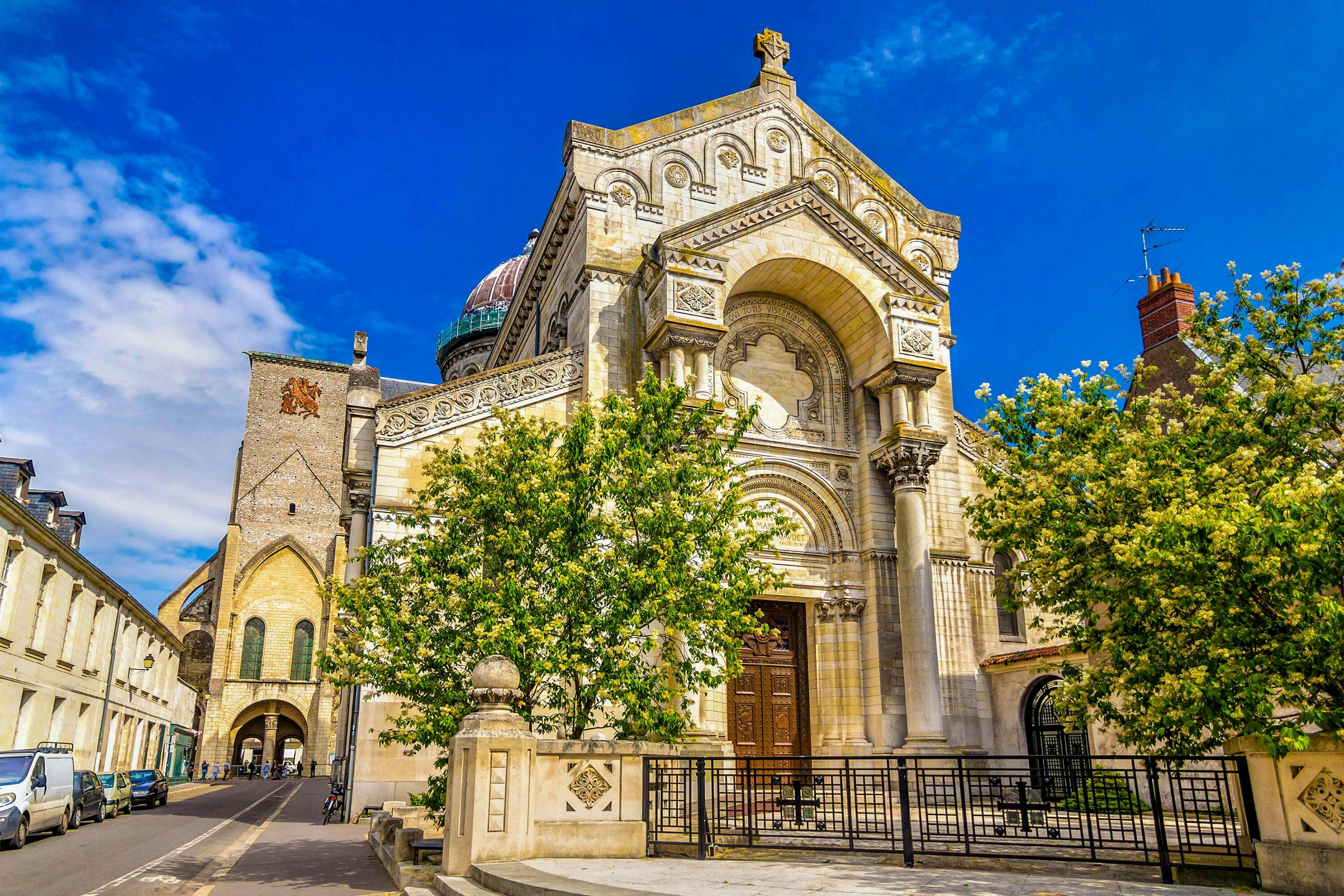 화려한 건축물과 나무가 앞에 있고, 맑고 푸른 하늘을 배경으로 한 유서 깊은 교회입니다.